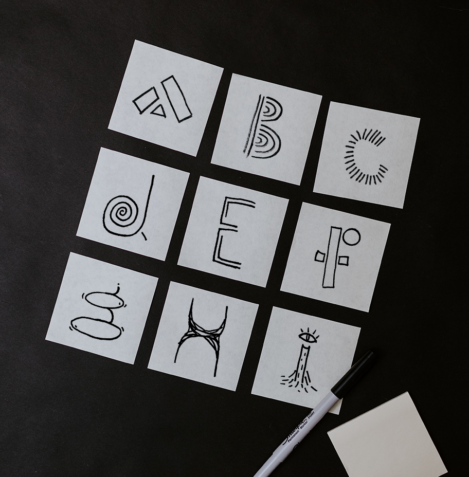 A 3 by 3 grid of paper squares with the sketches of the letters A through I.