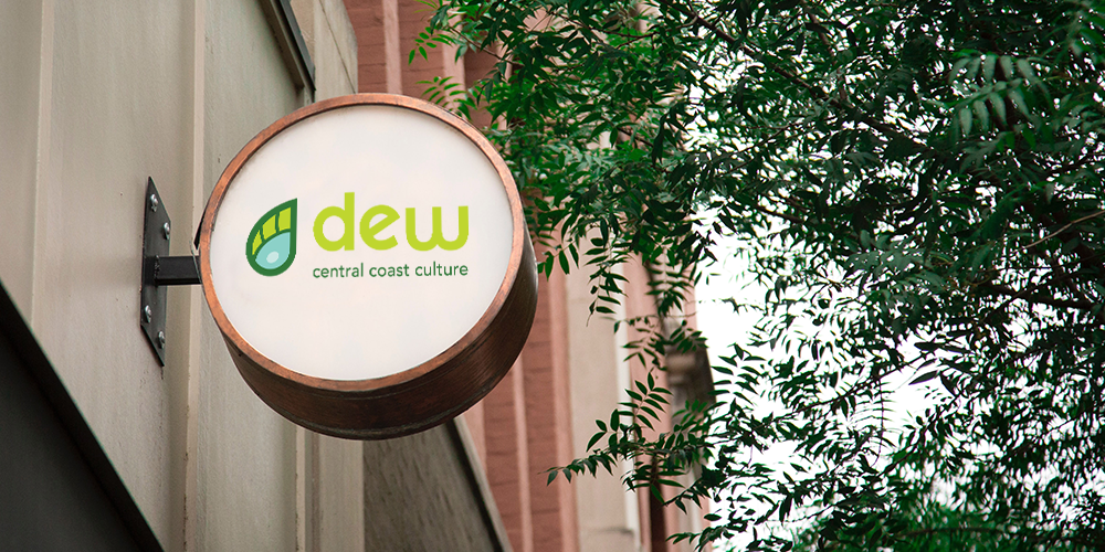 A circular sign containing the Dew logo mounted on the side of a building.