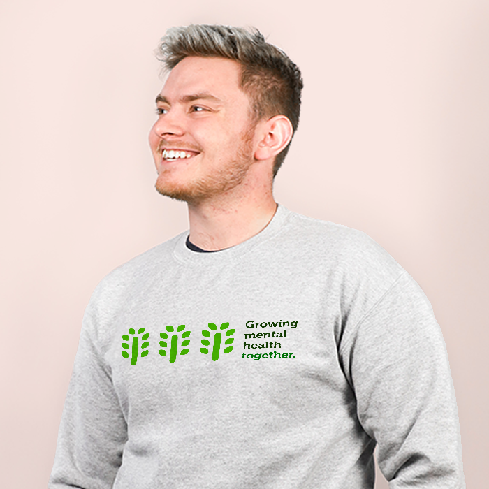 A smiling man in a grey sweatshirt with the phrase “Growing mental health together” and three Grove symbols across the front.
