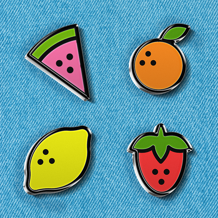 Four enamel pins of simple fruit icons: a watermelon, an orange, a lemon, and a strawberry.
